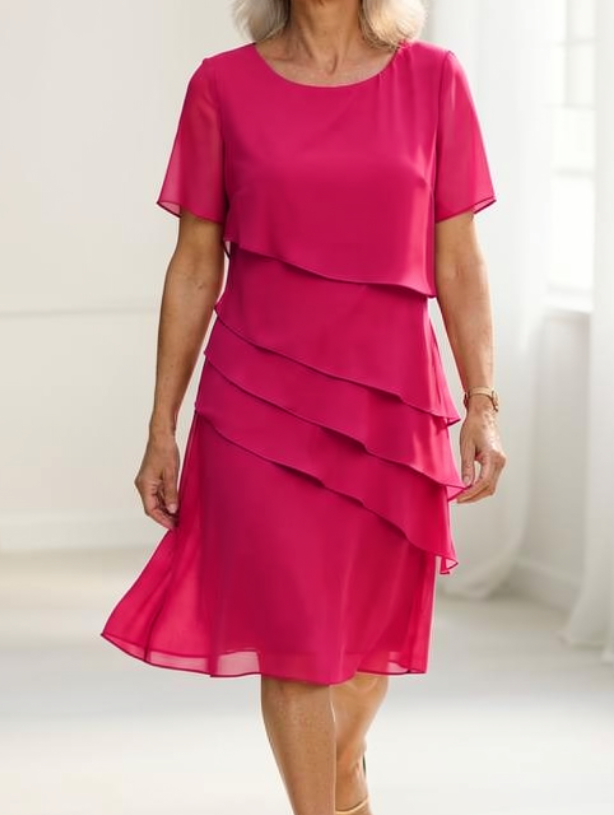 Robe fluide rose vif à volants superposés, manches courtes, jupe mi-longue.