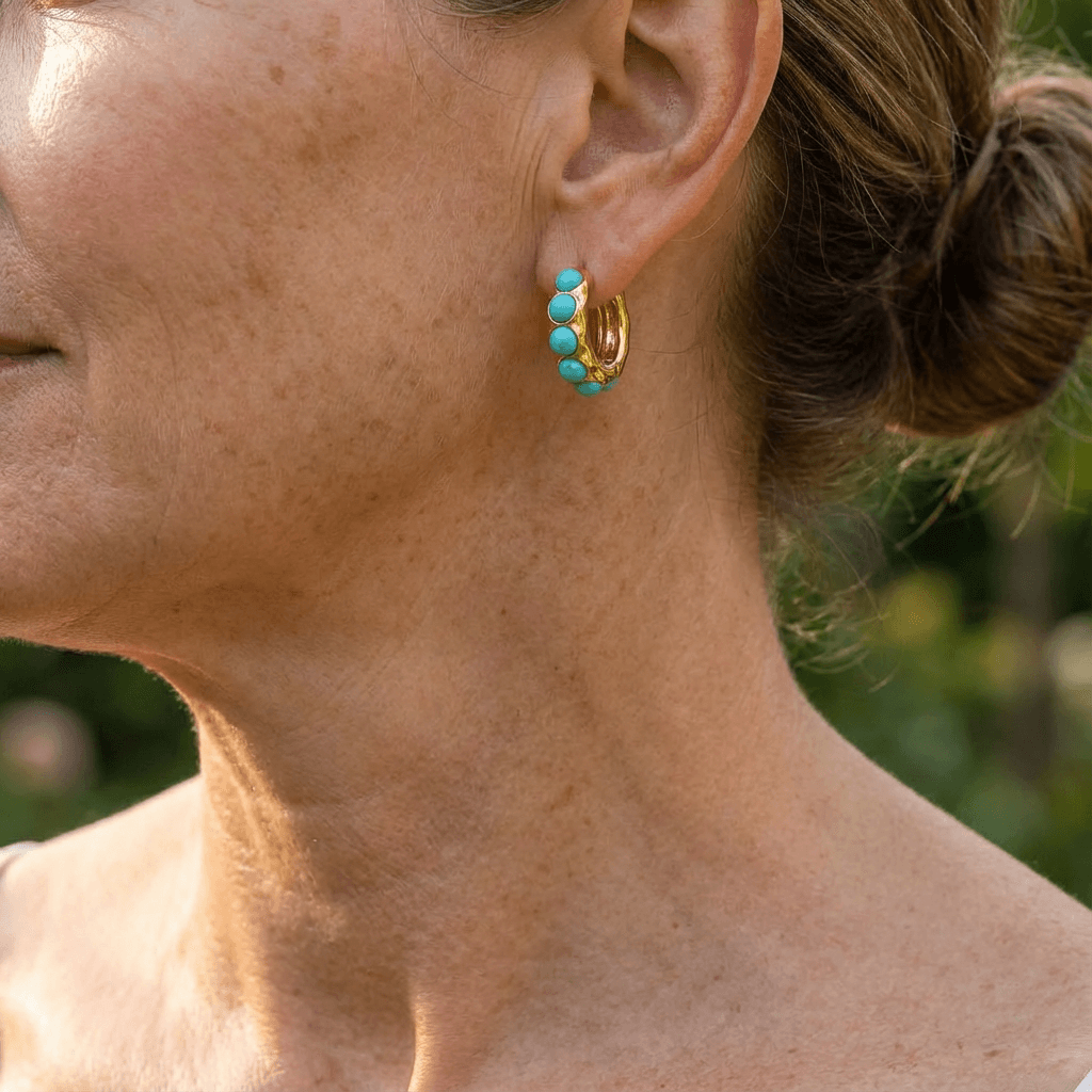 Créoles dorées ornées de pierres turquoise, vue de profil sur l’oreille