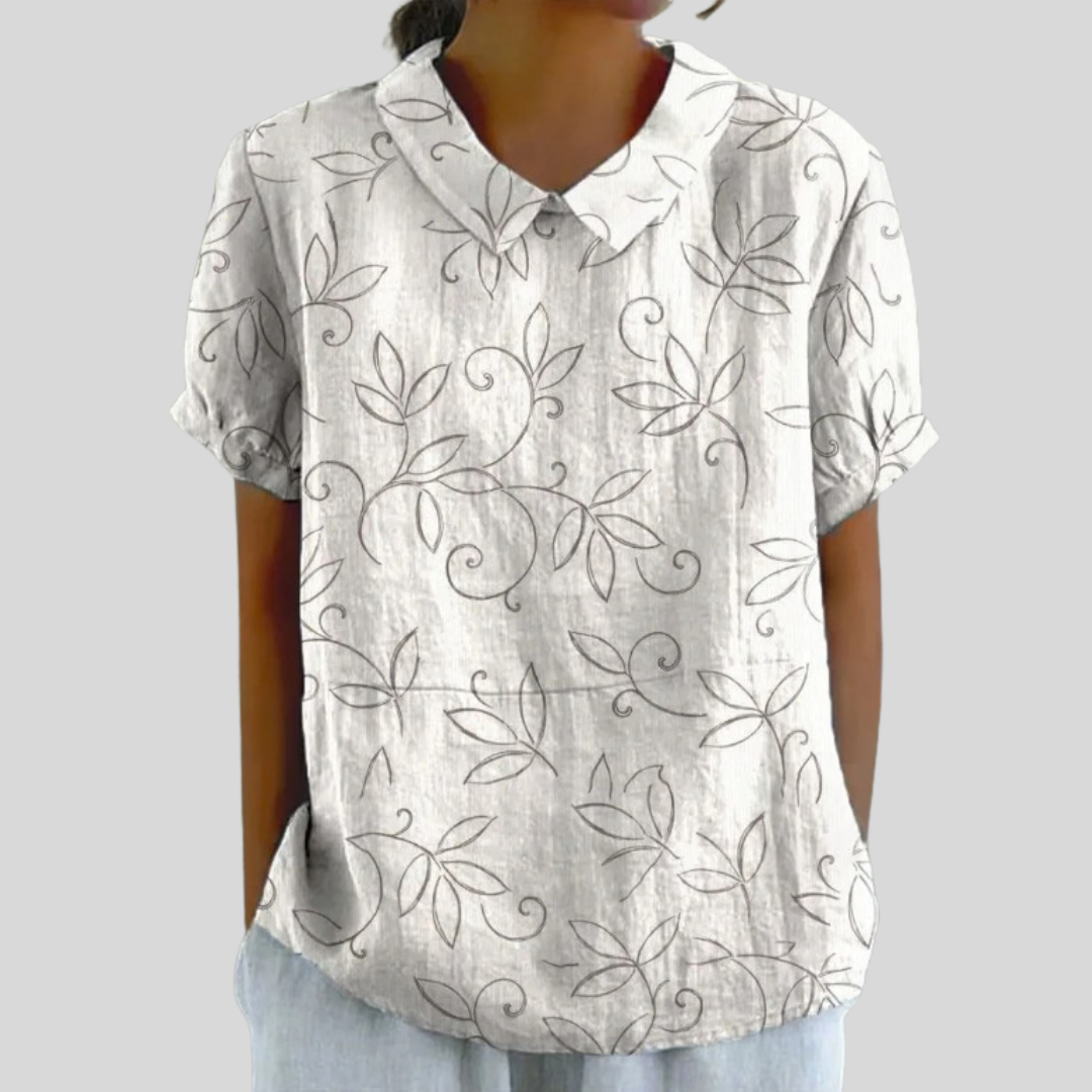 Blouse col classique à manches courtes, fond clair avec motif feuillages gris