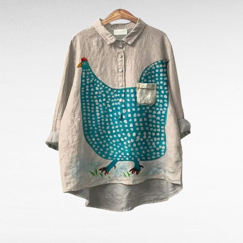 Blouse beige à motif de volaille turquoise, col chemise et boutons devant.