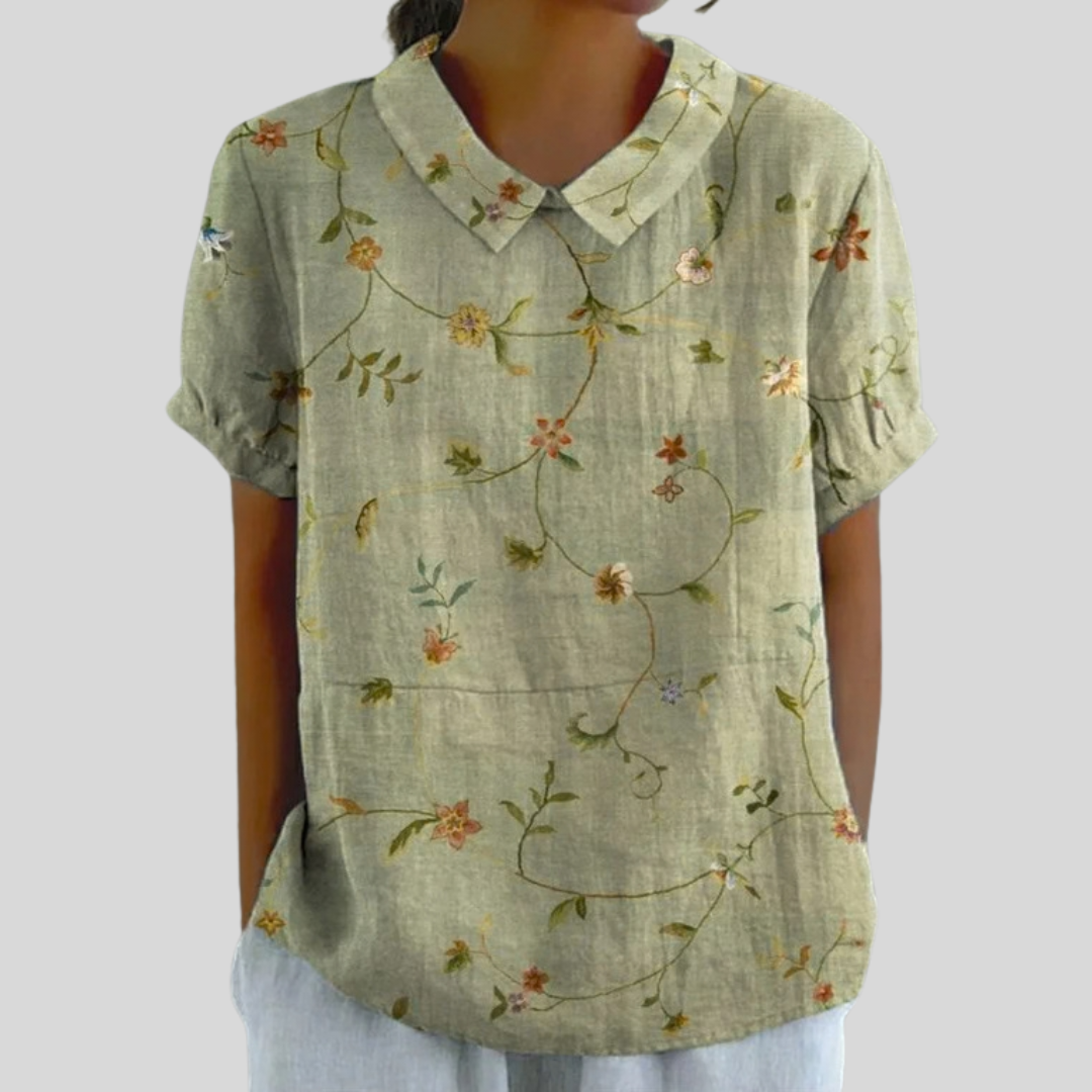 Blouse à col chemise manches courtes, fond vert clair et fleurs champêtres multicolores.