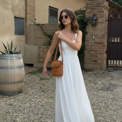 Sac bandoulière en cuir brun, porté à l’épaule, poche zippée et bandoulière.