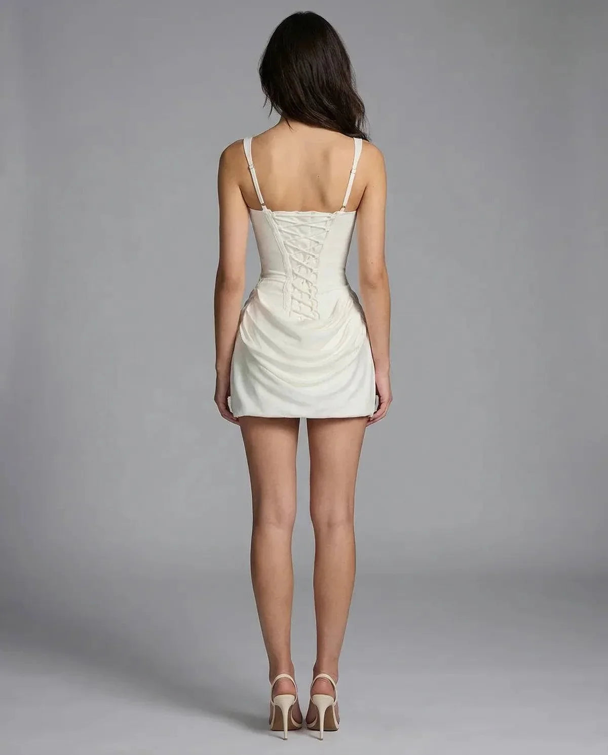 Robe courte blanche, dos à bretelles fines, corsage à plis et fronces.