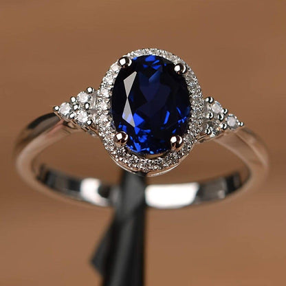 Bague saphir ovale bleu nuit, monture argent, entourage de pierres et griffes