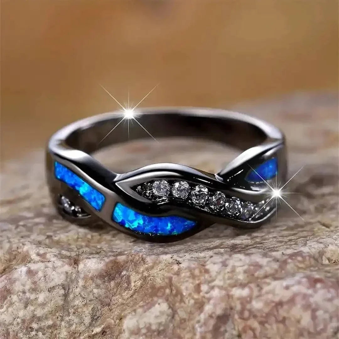 Bague Thessia Lunebray noire, inserts bleu opale et rangée de pierres brillantes.