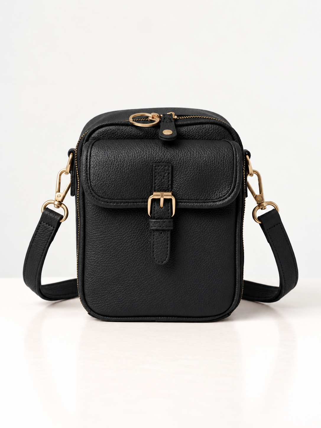 Sac bandoulière noir en cuir synthétique, rabat avec boucle dorée et sangle réglable