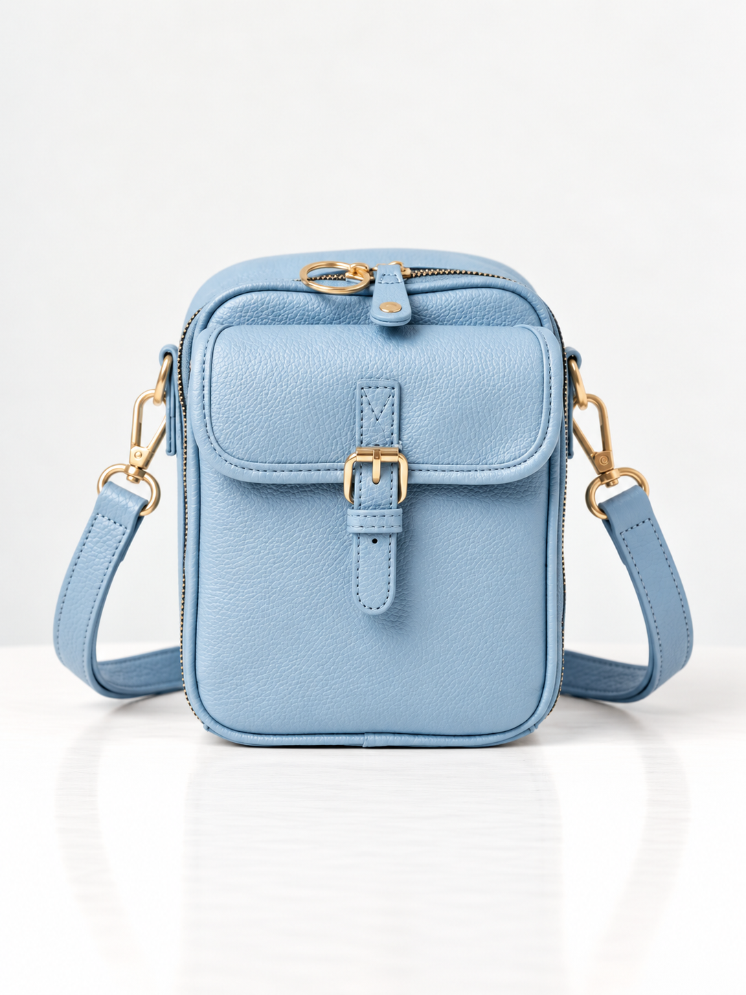 Sac bandoulière bleu clair en cuir synthétique, rabat avec boucle dorée et sangle réglable
