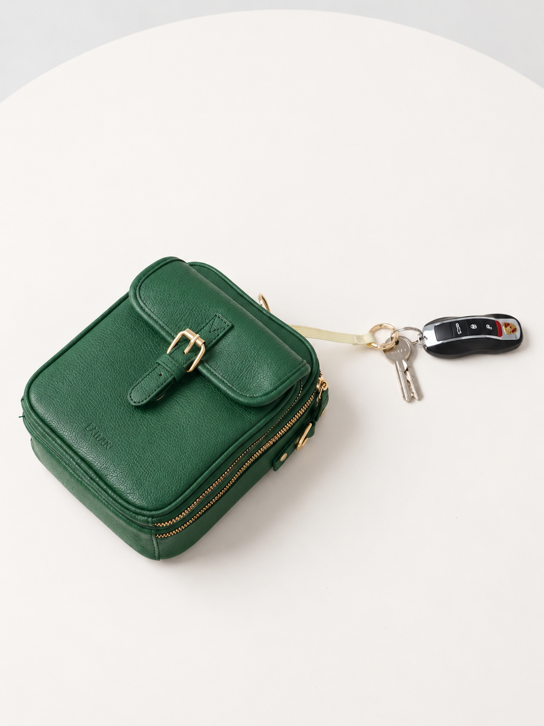 Petit sac bandoulière vert en cuir, fermeture zippée, porte-clés avec mousqueton.