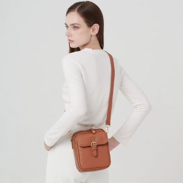 Sac bandoulière brun caramel en cuir synthétique, porté sur l’épaule avec sangle réglable