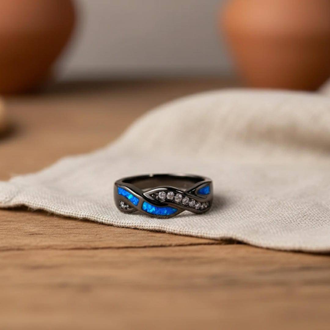 Bague Thessia Lunebray noire, pierres bleues et motifs sertis de petites pierres claires.