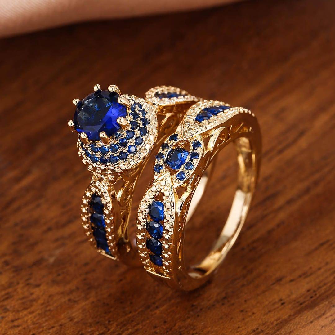 Deux bagues métal doré avec pierres bleues, motif entrelacé et rangées scintillantes