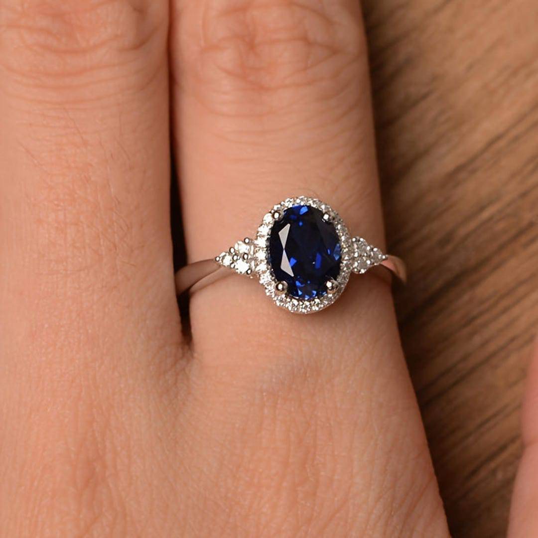 Bague saphir ovale bleu nuit, entourage pavé de pierres, vue sur le doigt