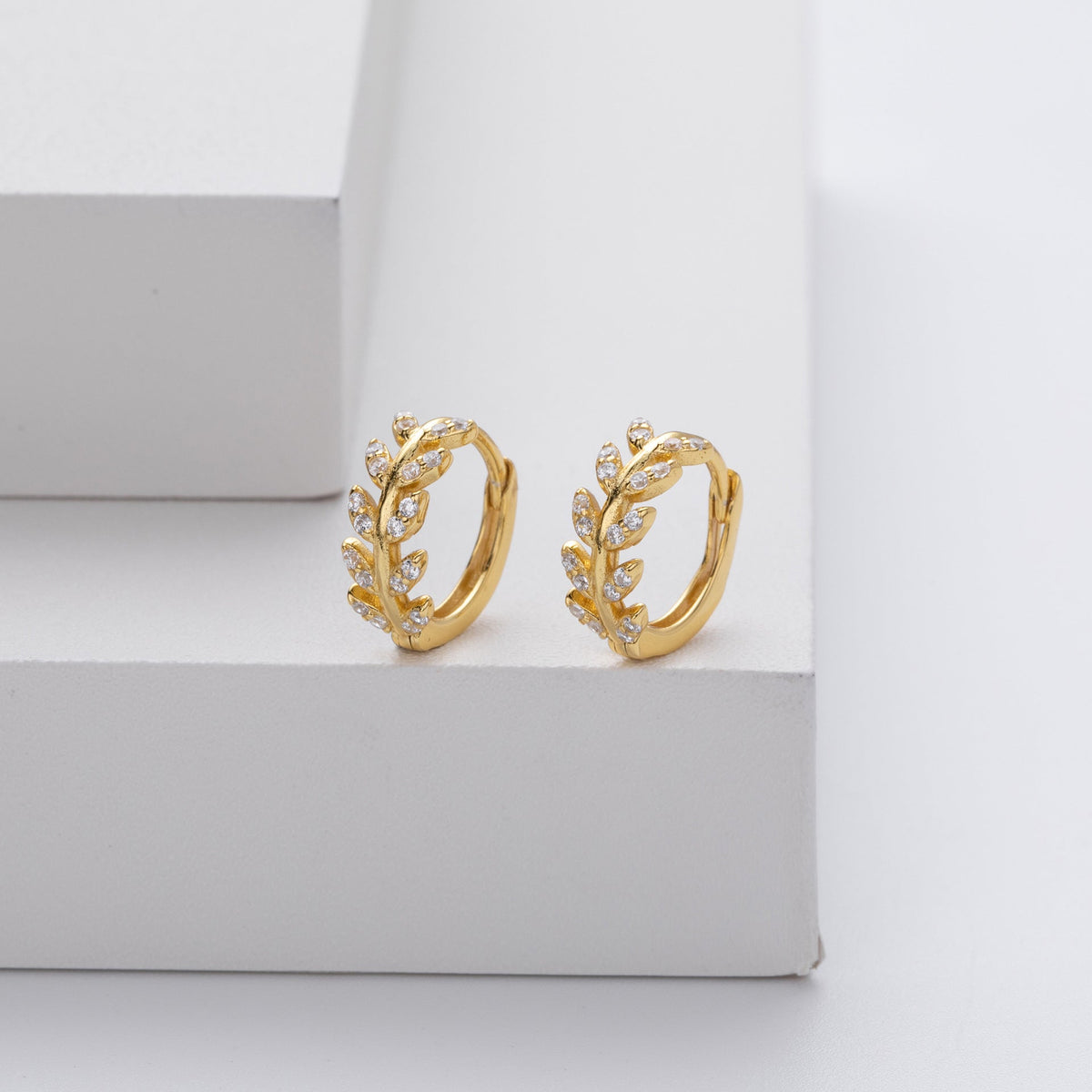 Boucles d’oreilles créoles dorées en forme de feuilles, décor détaillé.