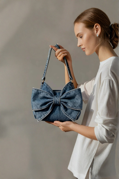 Sac à nœud rétro en denim bleu, porté en bandoulière, grand nœud frontal.