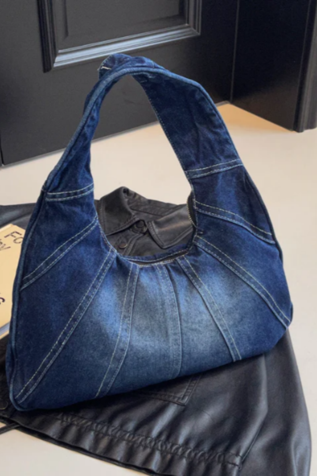 Grand sac hobo en jean bleu foncé, anses larges et bandoulière.