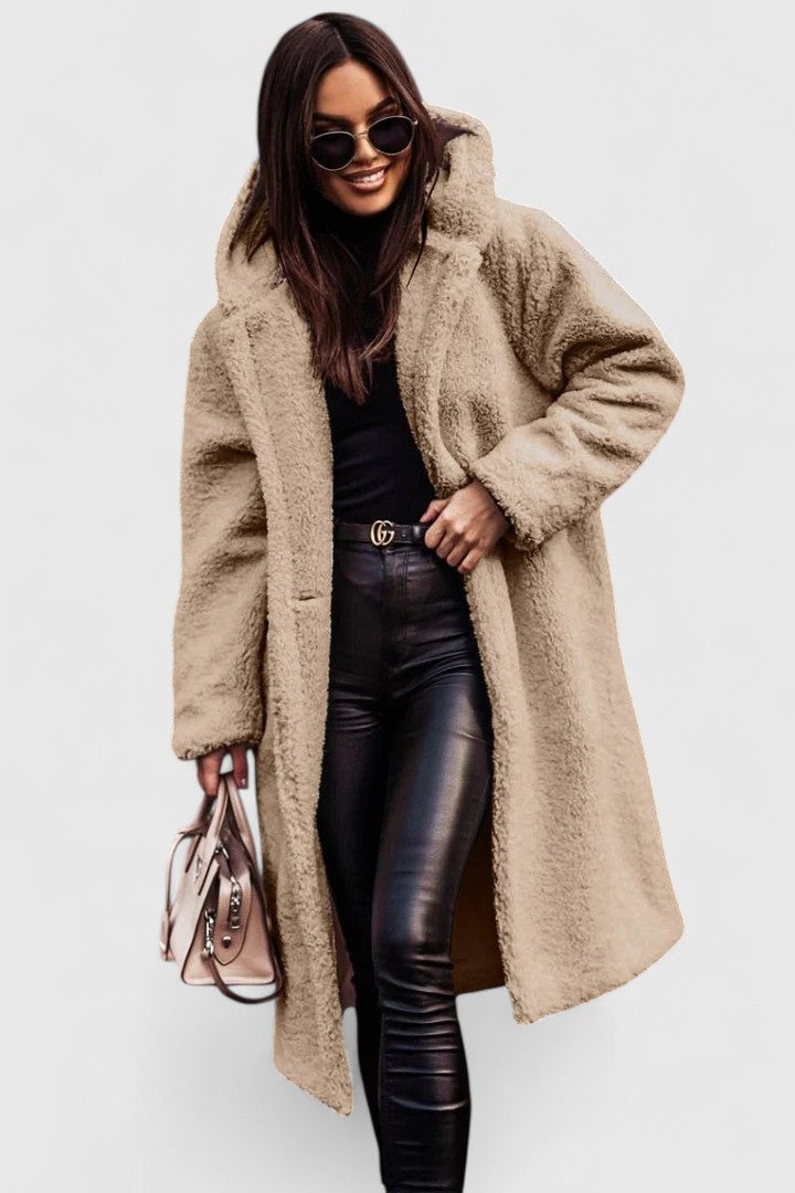 Veste longue en tissu bouclé beige clair, col châle, poches et boutonnage discret.
