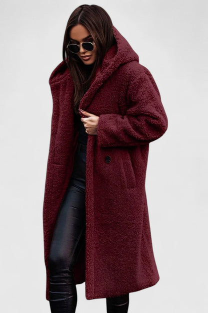 Veste longue en tissu bouclé bordeaux, col châle, poches et boutonnage discret.
