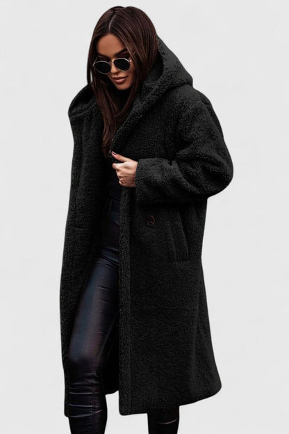 Veste longue en tissu bouclé noir, col châle, poches et boutonnage discret.