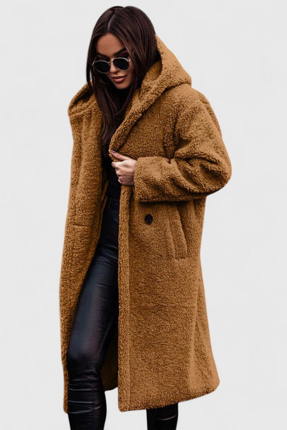 Veste longue en tissu bouclé camel, col châle, poches et boutonnage discret.