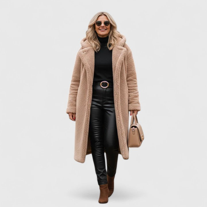 Veste longue en tissu bouclé beige clair, col châle, poches et boutonnage discret.