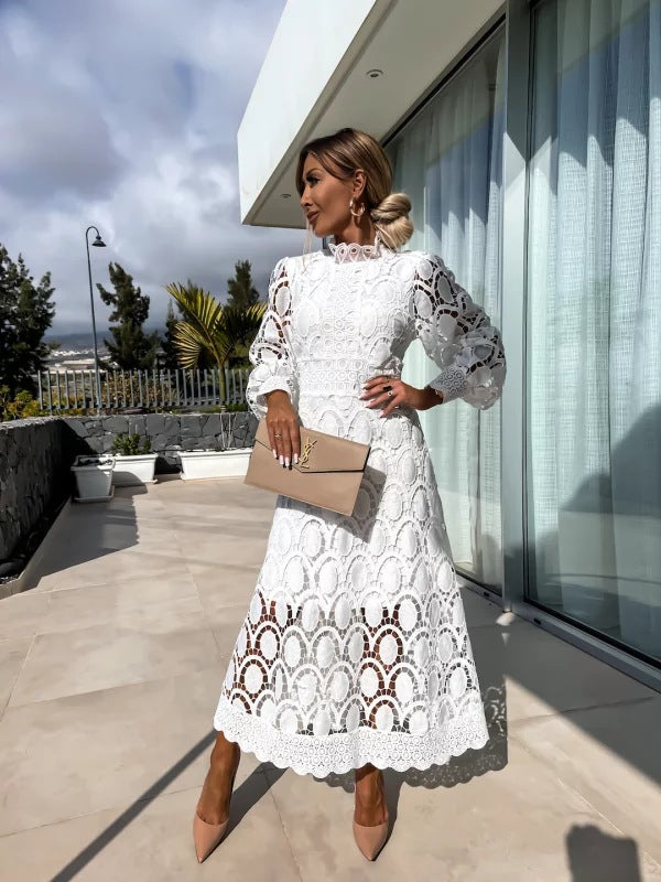 Robe en dentelle romantique blanche, manches longues bouffantes, col haut, motif ajouré.