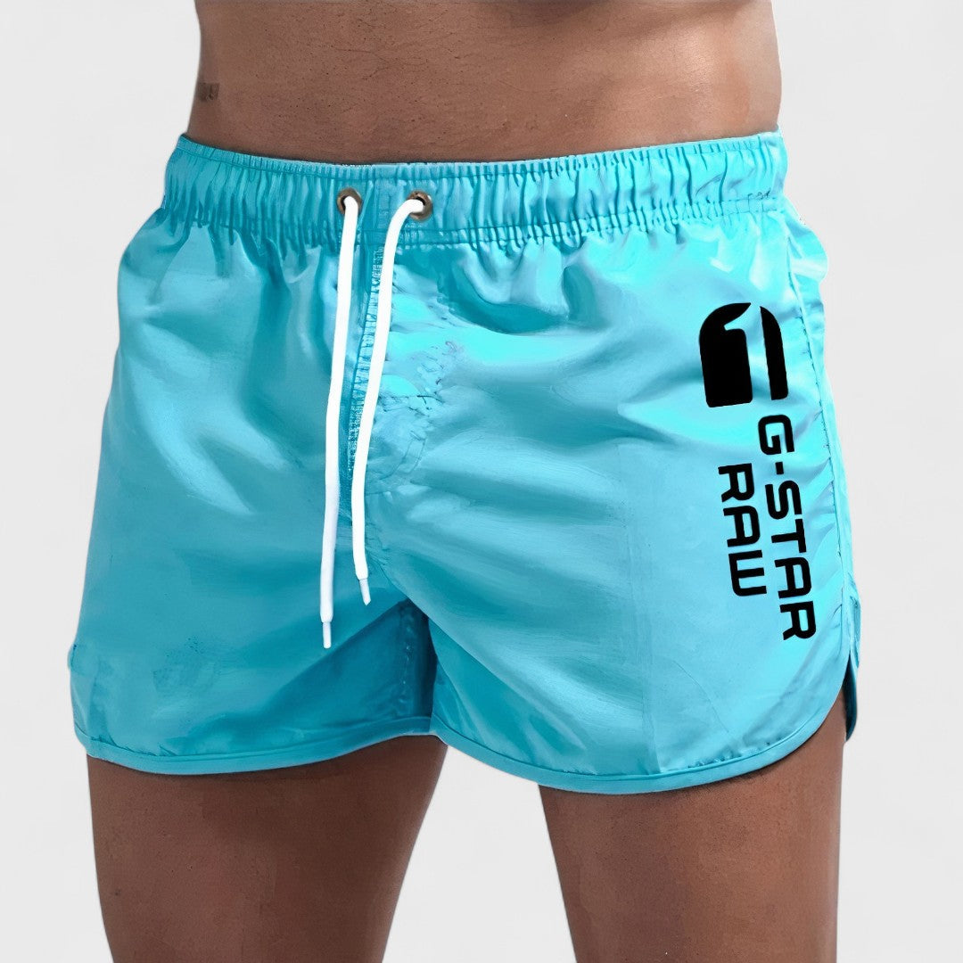 Short de bain homme bleu turquoise, cordon blanc et logo sur la jambe.