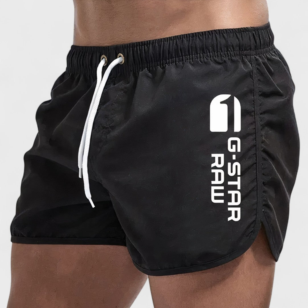 Short de bain homme noir, cordon blanc, logo imprimé sur la jambe.