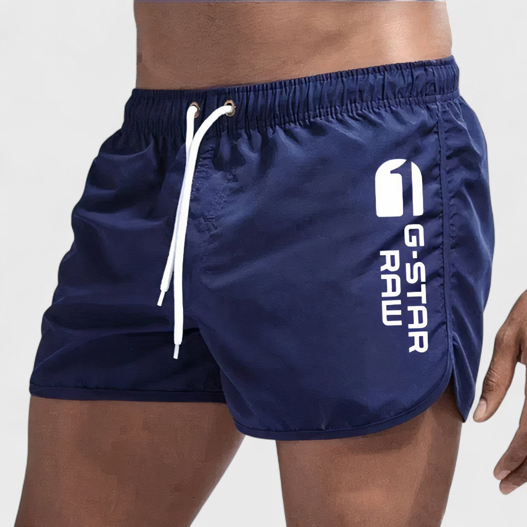 Short de bain homme bleu marine, cordon blanc, logo imprimé sur la jambe.