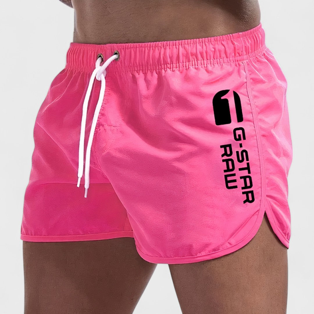 Short de bain homme rose fuchsia, cordon blanc, logo imprimé sur la jambe.