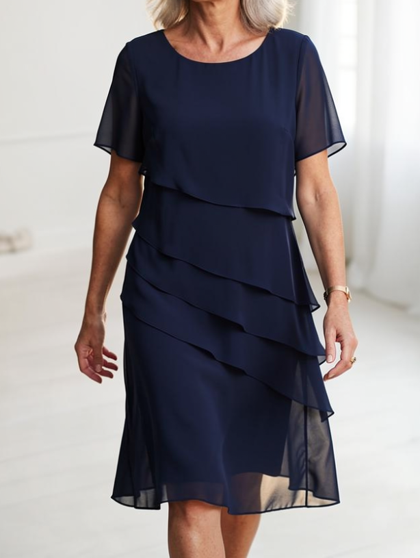 Robe fluide bleue foncée à volants superposés, manches courtes, coupe mi-longue.