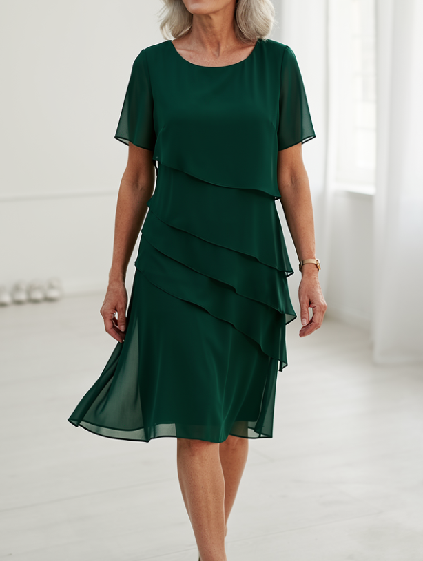 Robe fluide verte à volants superposés, manches courtes, jupe mi-longue.