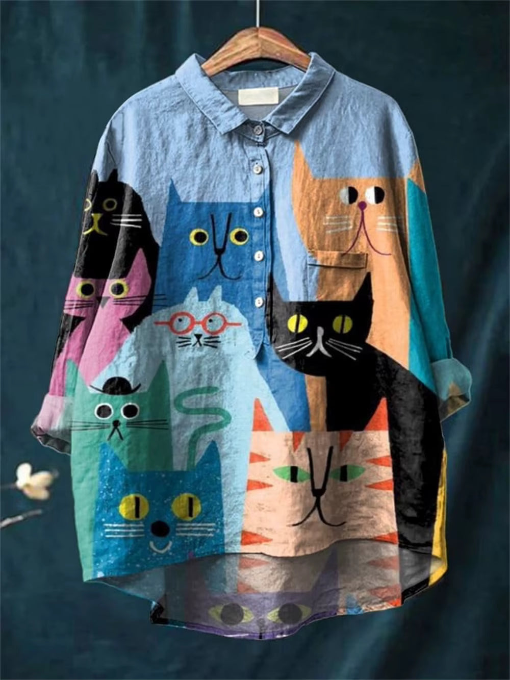 Blouse ample bleu clair à imprimé chats et personnages, boutons devant, col chemise.