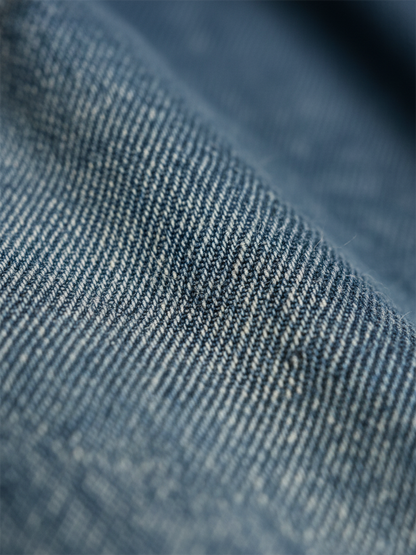Tissu denim bleu délavé, grain fin et texture tissée visible