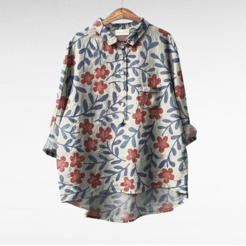 Blouse à col chemise beige-bleu, fleurs rouges et bleues, boutonnée, manches trois-quarts.