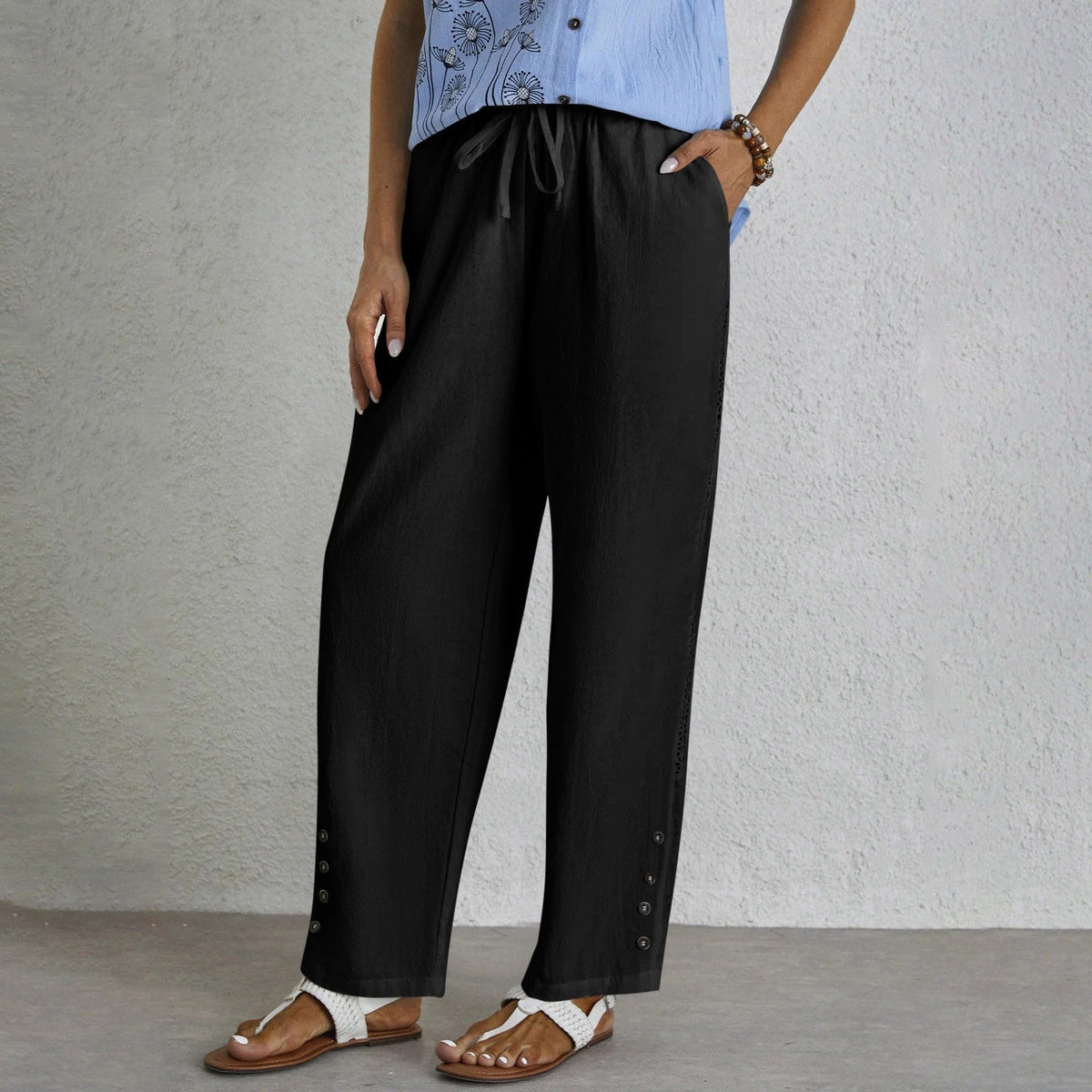 Pantalon ample noir avec cordon à la taille, boutons sur le côté et ourlet ajouré