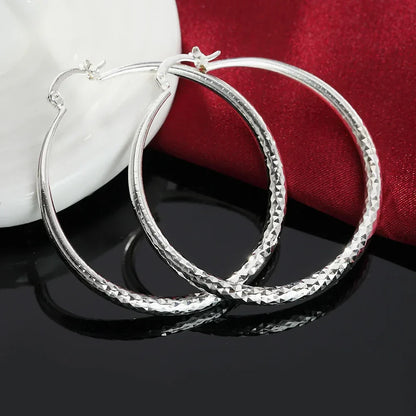 Boucles d’oreilles créoles en argent sterling, vue profil avec texture sur la circonférence.