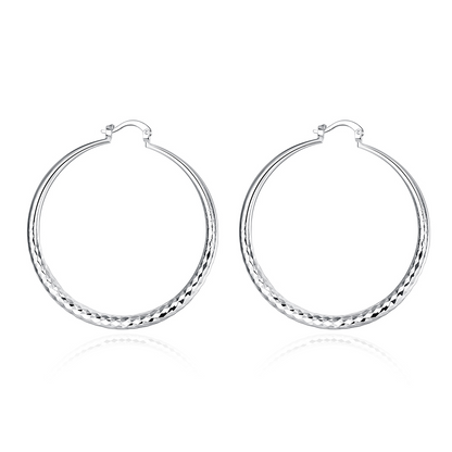 Boucles d’oreilles créoles en argent, anneau arrondi avec bord texturé en bas.