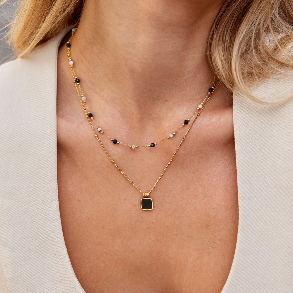 Collier multicouche doré à perles bleu foncé et breloque carrée sur le cou