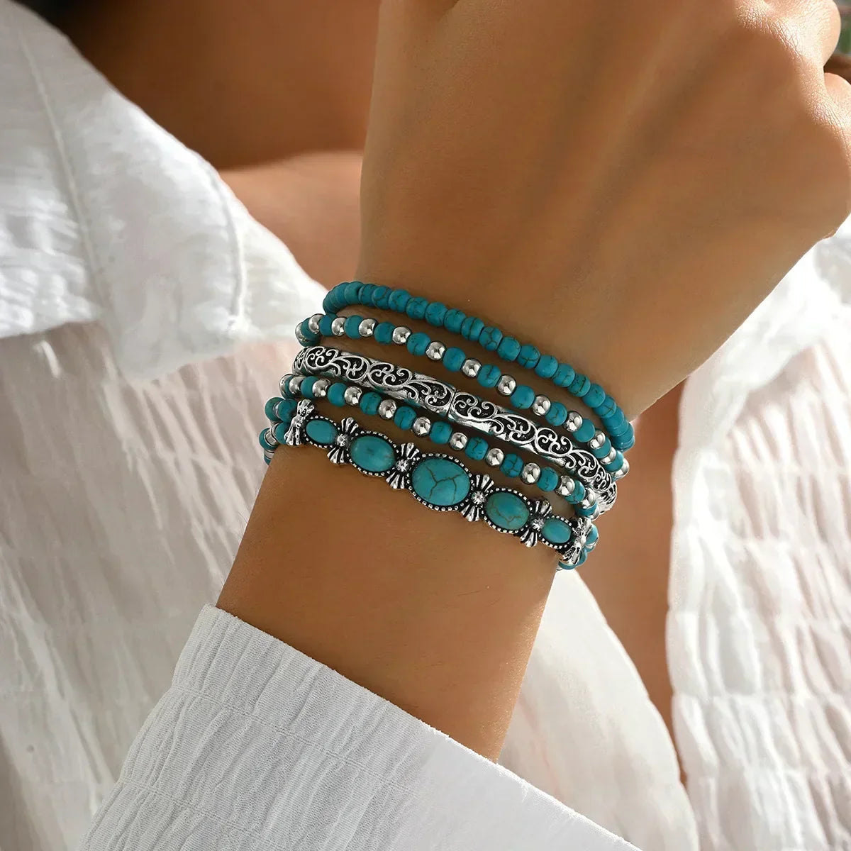 Bracelets perles turquoise et breloques ovales argentées, superposés au poignet