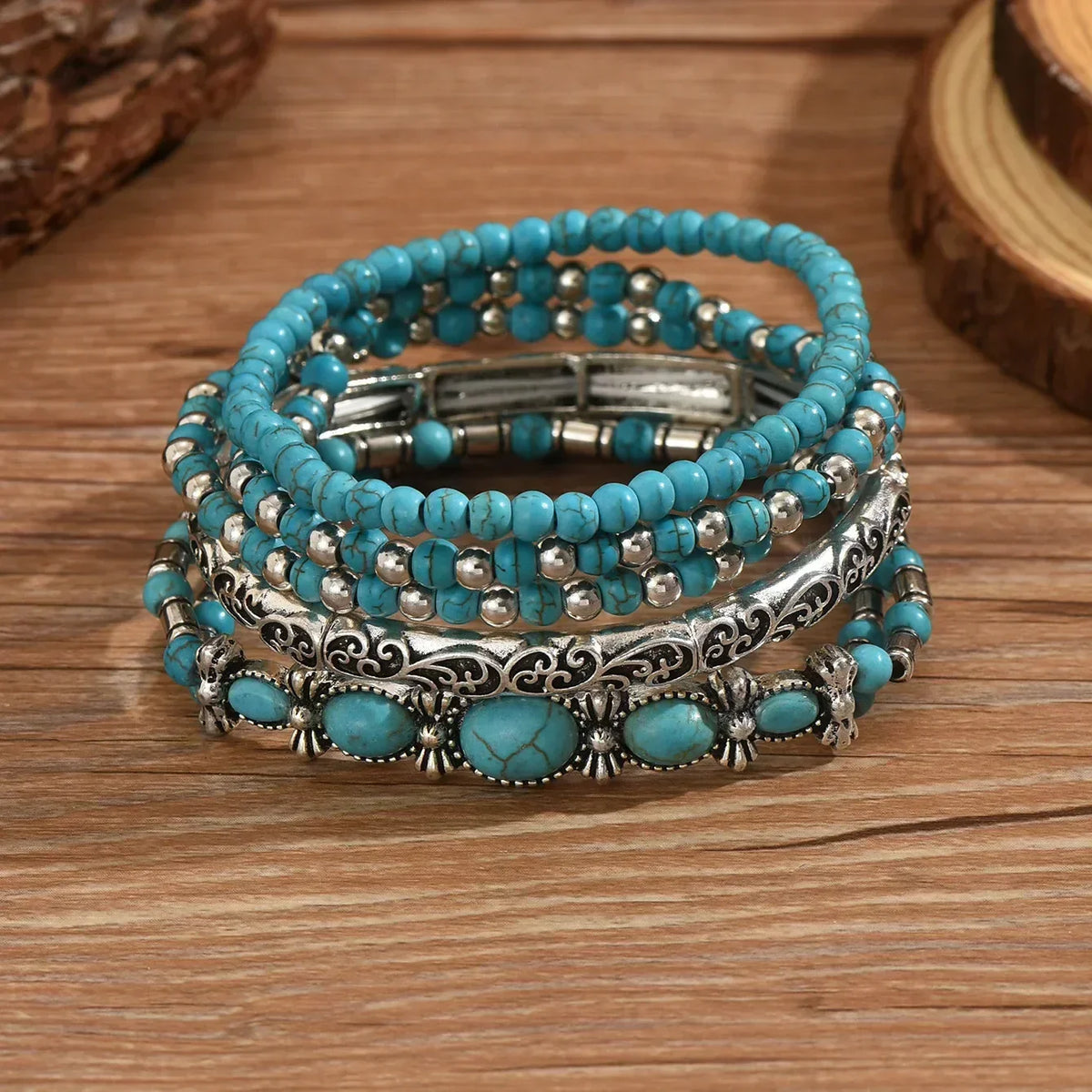 Bracelets perles turquoise avec fermoir métal et motifs argentés, posés sur bois