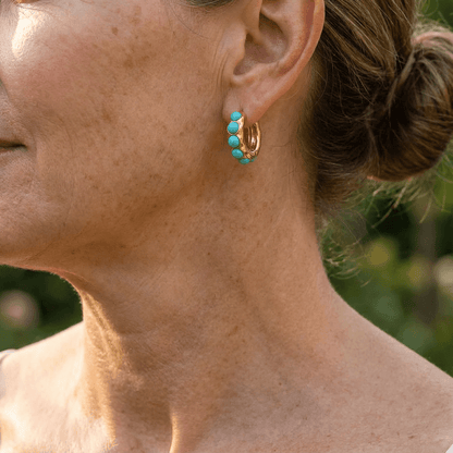 Créoles dorées ornées de pierres turquoise, vue de profil sur l’oreille