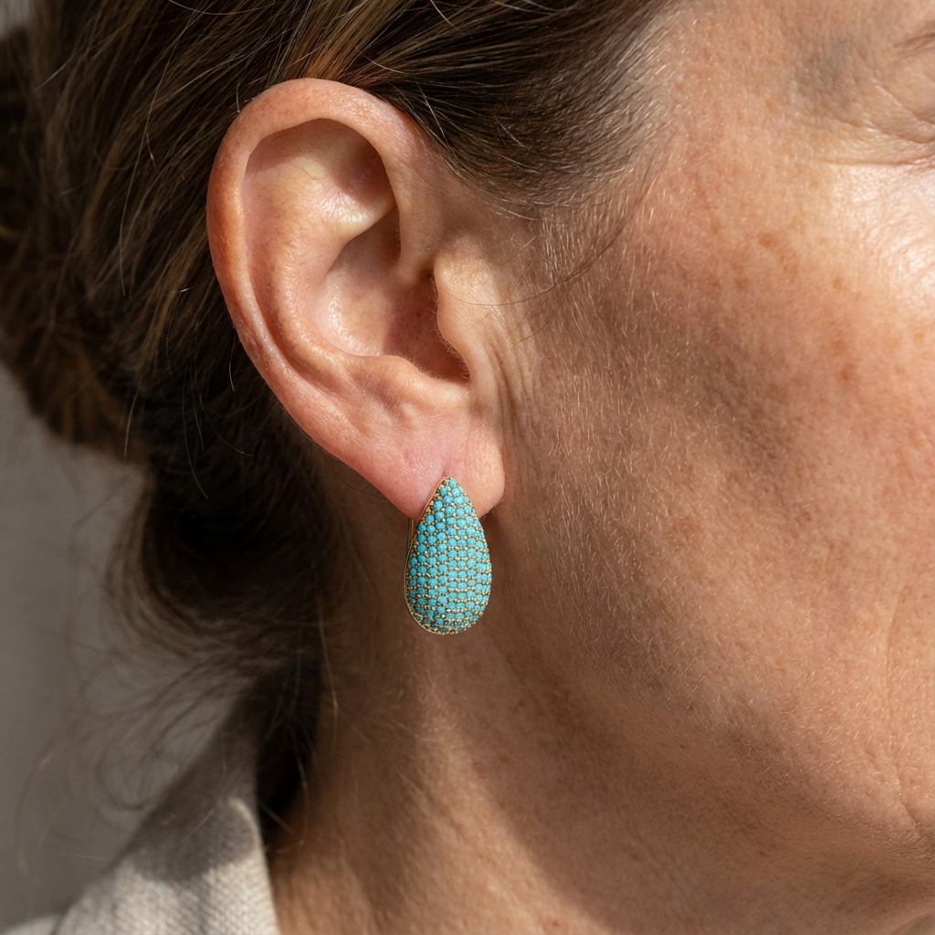 Boucles d’oreilles larme turquoise, monture dorée, portées sur l’oreille