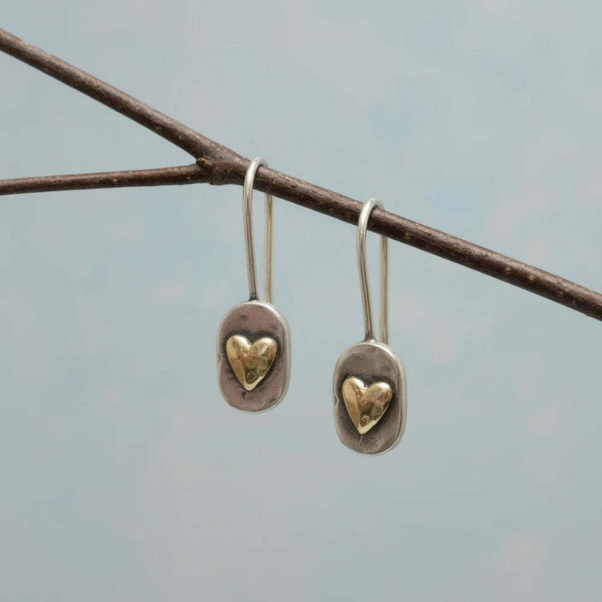 Boucles d’oreilles pendantes avec cœur doré incrusté sur support ovale argenté