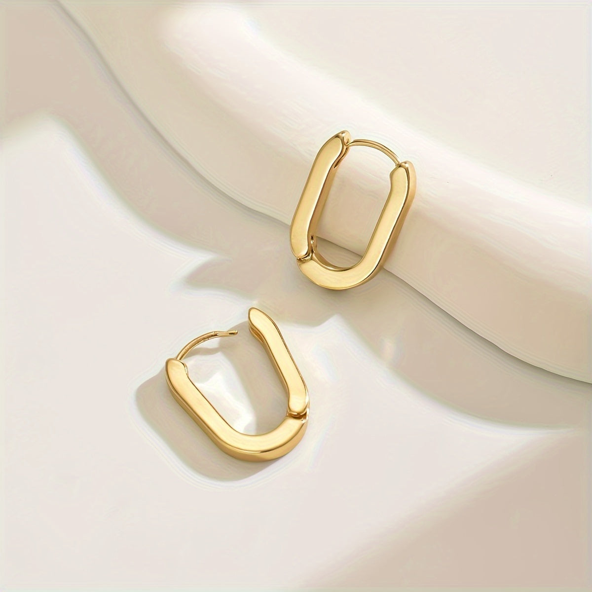 Paire de boucles créoles dorées ovales, contours géométriques, vue rapprochée