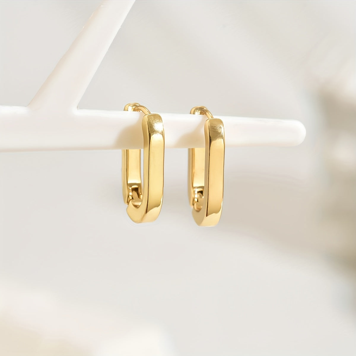 Paire de boucles créoles dorées à anneau ovale, face avant, finition brillante