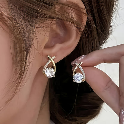 Puces d’oreilles croix dorée avec zirconium transparent, portées sur l’oreille