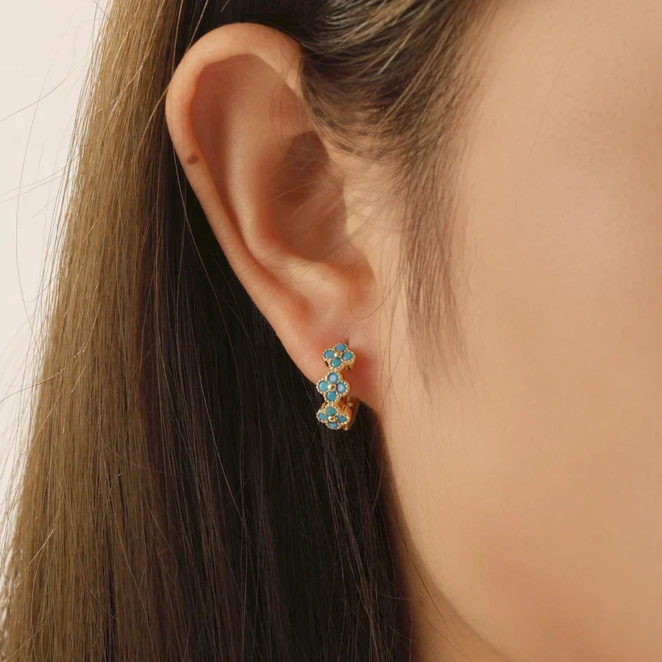 Boucles d’oreilles créoles dorées avec motif fleurs turquoise sur l’oreille