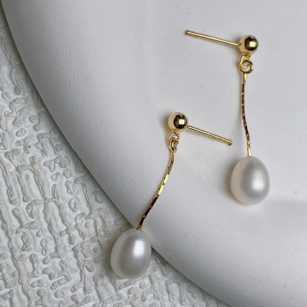 Boucles d’oreilles dorées à perle blanche pendante, fermoir à tige.