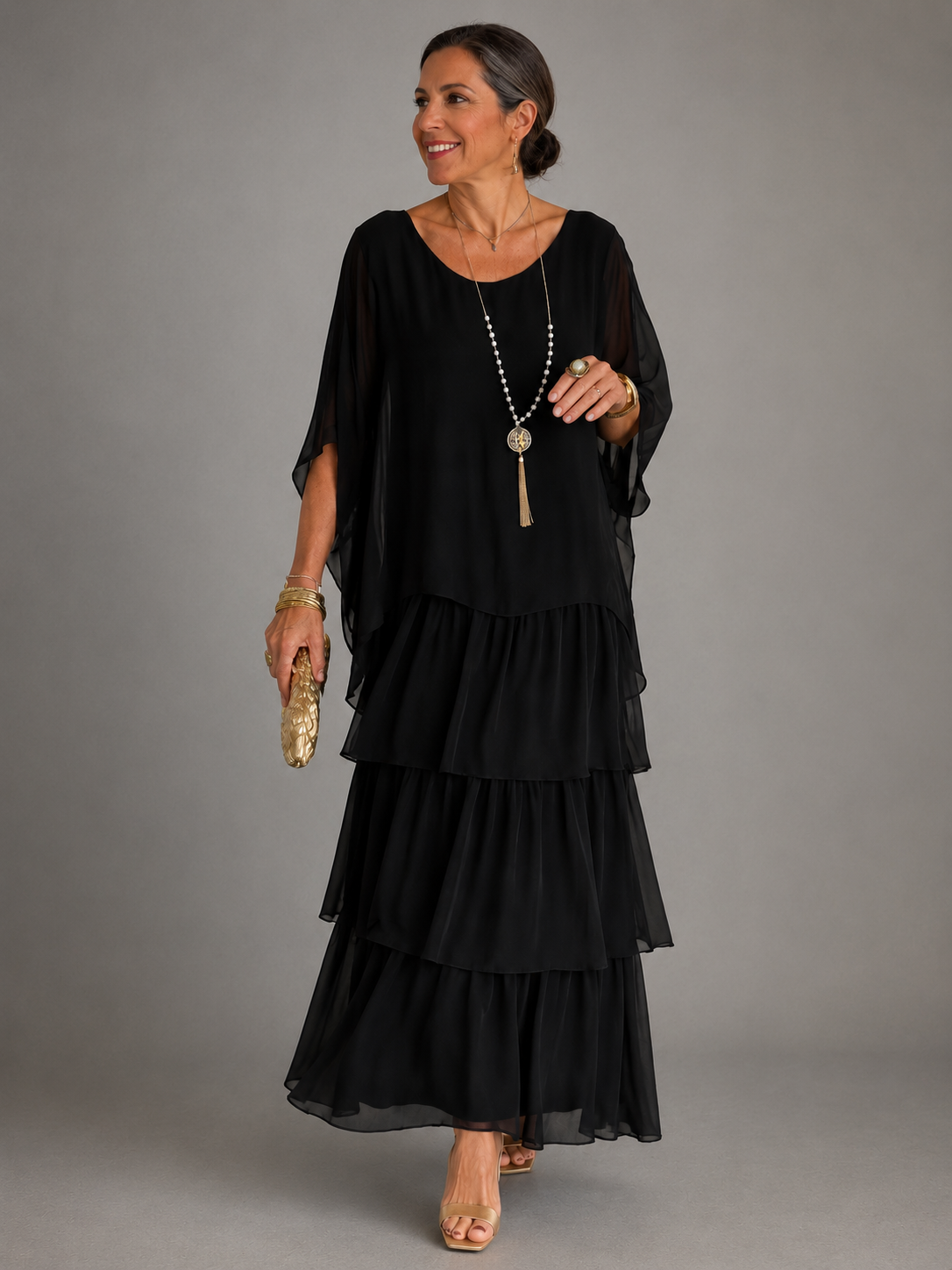 Robe longue fluide noire à volants étagés, manches chauve-souris, encolure ronde.