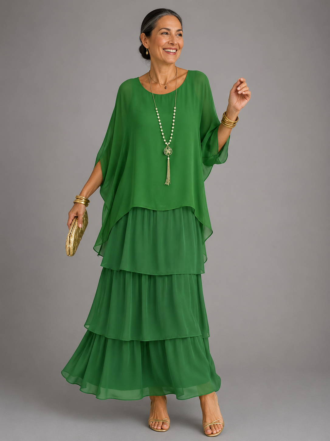 Robe longue fluide verte à volants étagés, manches chauve-souris, encolure ronde.
